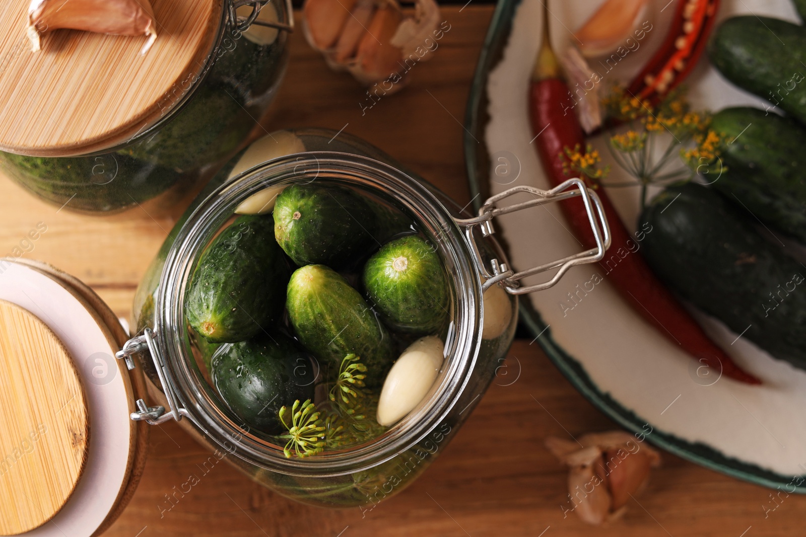 Photo of Jar with cucumbers, garlic and dill on wooden table, top view. Pickling recipe