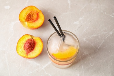 Photo of Tasty peach cocktail in glass on table. Refreshing drink