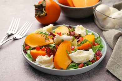 Delicious persimmon salad with cheese and pomegranate served on grey table