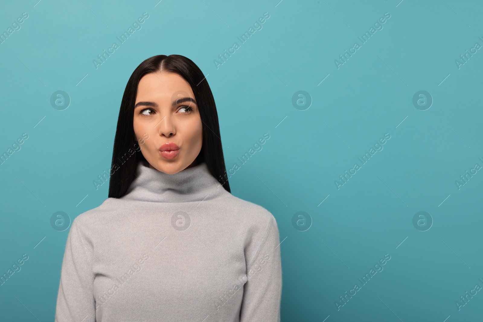 Photo of Beautiful young woman blowing kiss on light blue background. Space for text