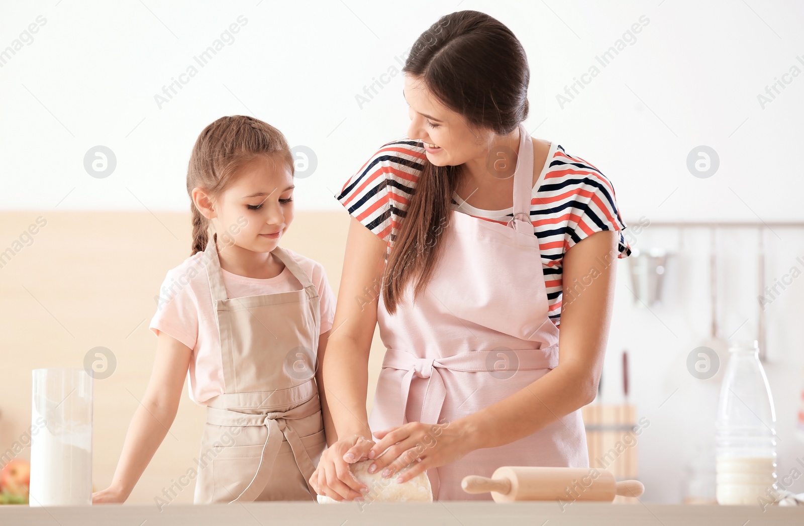 Photo of Mother and her daughter preparing dough at table in kitchen