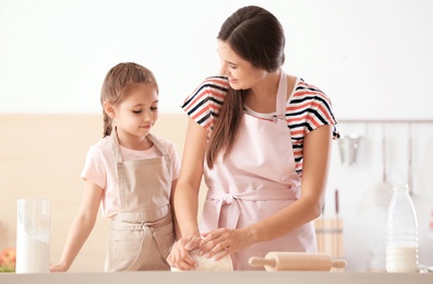 Photo of Mother and her daughter preparing dough at table in kitchen