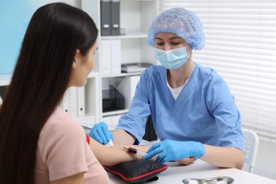 Laboratory testing. Doctor taking blood sample from patient at white table in hospital