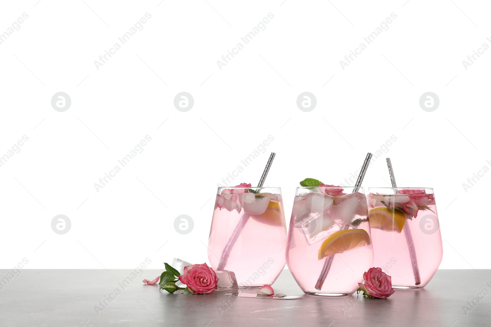 Photo of Delicious refreshing drink with rose flowers and lemon slices on light grey table against white background. Space for text