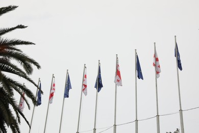 Photo of BATUMI, GEORGIA - MAY 31, 2022: Many flags of Georgia and European Union on poles outdoors, low angle view