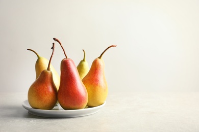 Plate with ripe pears on light background. Space for text