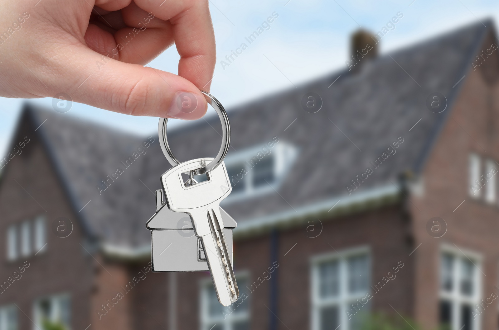 Image of Woman holding key near house outdoors, closeup