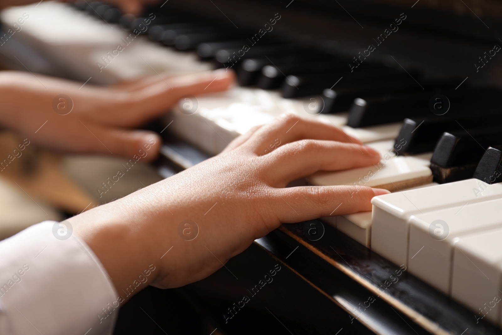 Photo of Little child playing piano, closeup. Music lesson