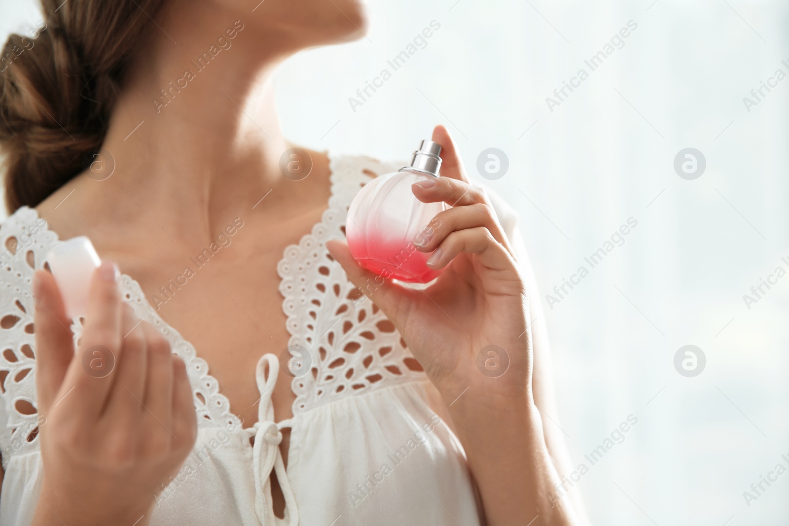 Photo of Young woman using perfume indoors, closeup. Space for text