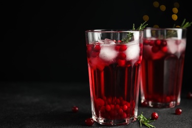 Tasty refreshing cranberry cocktail with rosemary on black table. Space for text