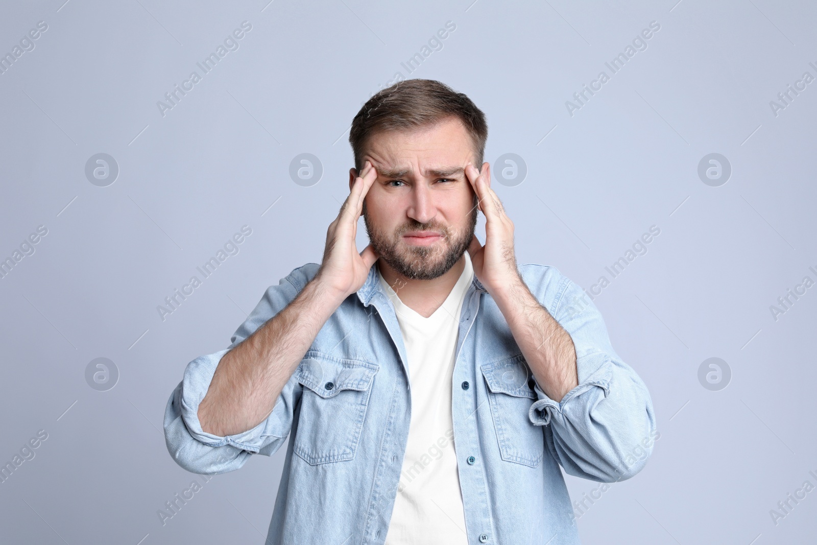 Photo of Young man suffering from headache on light background