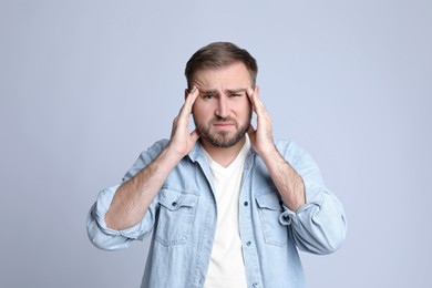 Photo of Young man suffering from headache on light background