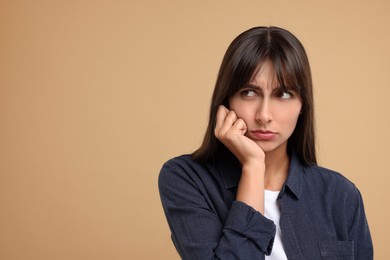 Resentful woman on beige background, space for text