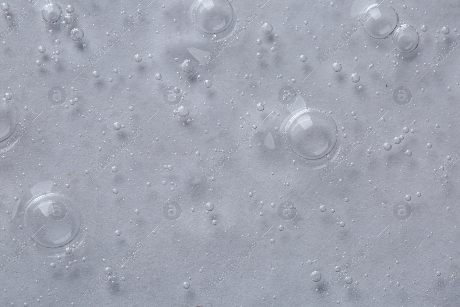 Photo of Clear cosmetic serum on light background, macro view