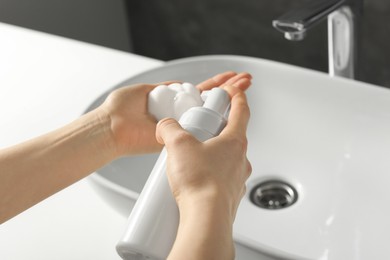 Photo of Woman washing hands with cleansing foam near sink in bathroom, closeup