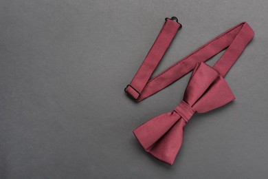 Photo of Stylish burgundy bow tie on dark background, top view. Space for text