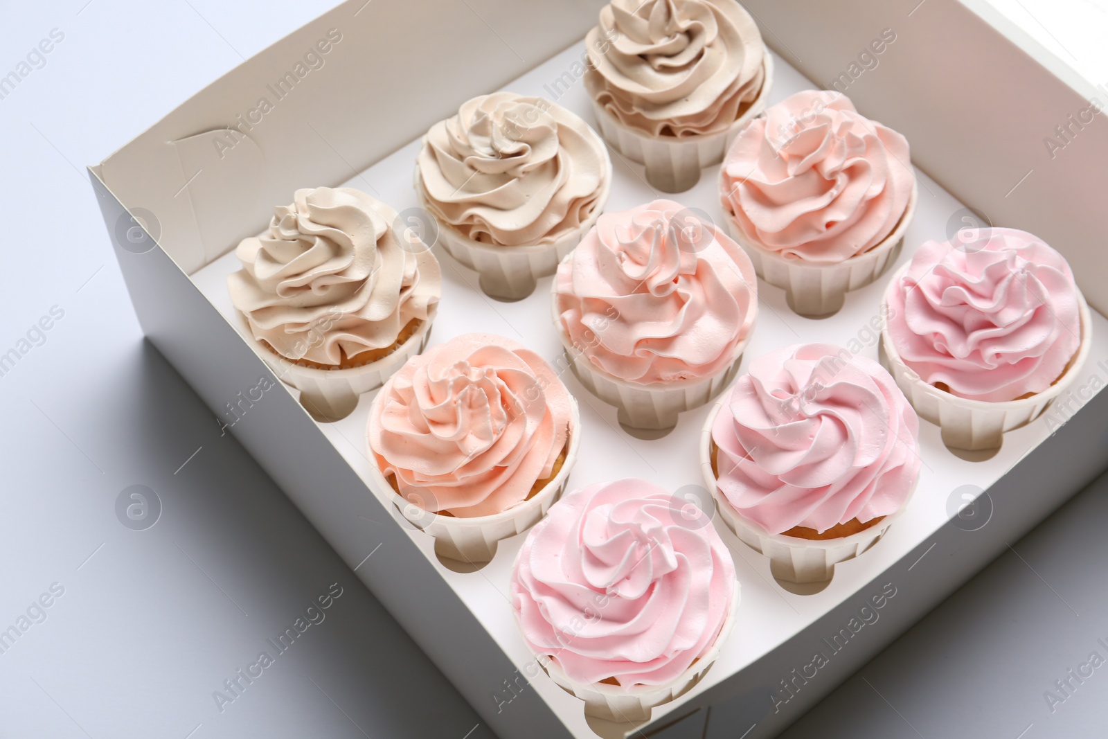 Photo of Tasty cupcakes in box on white background, closeup