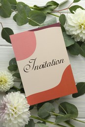 Card with word Invitation and beautiful flowers on white wooden background, flat lay