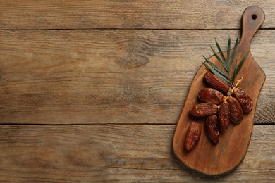 Sweet dried dates with leaf on wooden table, top view. Space for text