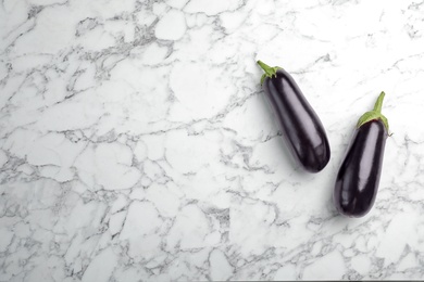 Photo of Raw ripe eggplants on marble background, top view