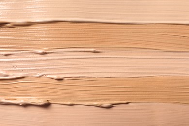 Photo of Samples of skin foundation as background, closeup