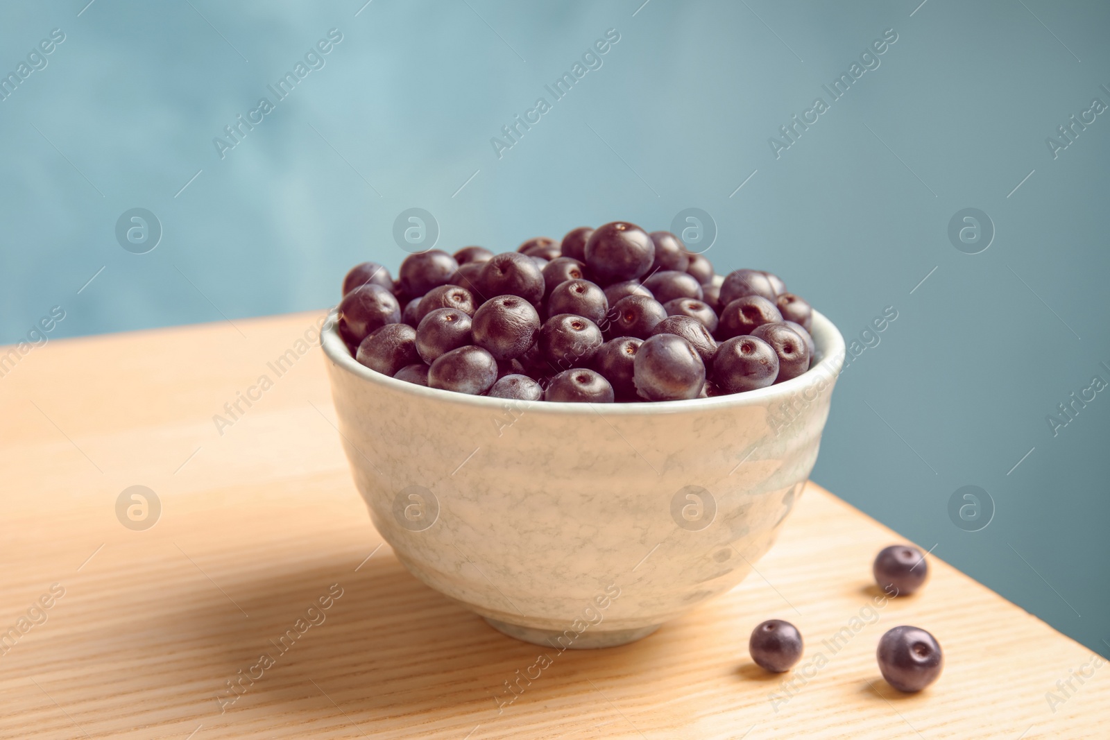 Photo of Bowl with fresh acai berries on table, closeup