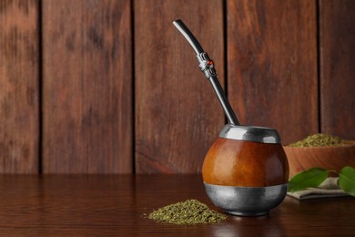 Photo of Calabash with mate tea and bombilla on wooden table. Space for text