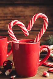 Photo of Cup of hot chocolate with Christmas candy canes on wooden table