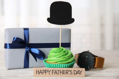 Photo of Composition of cupcake, wristwatch and gift box on white wooden table. Happy Father's day