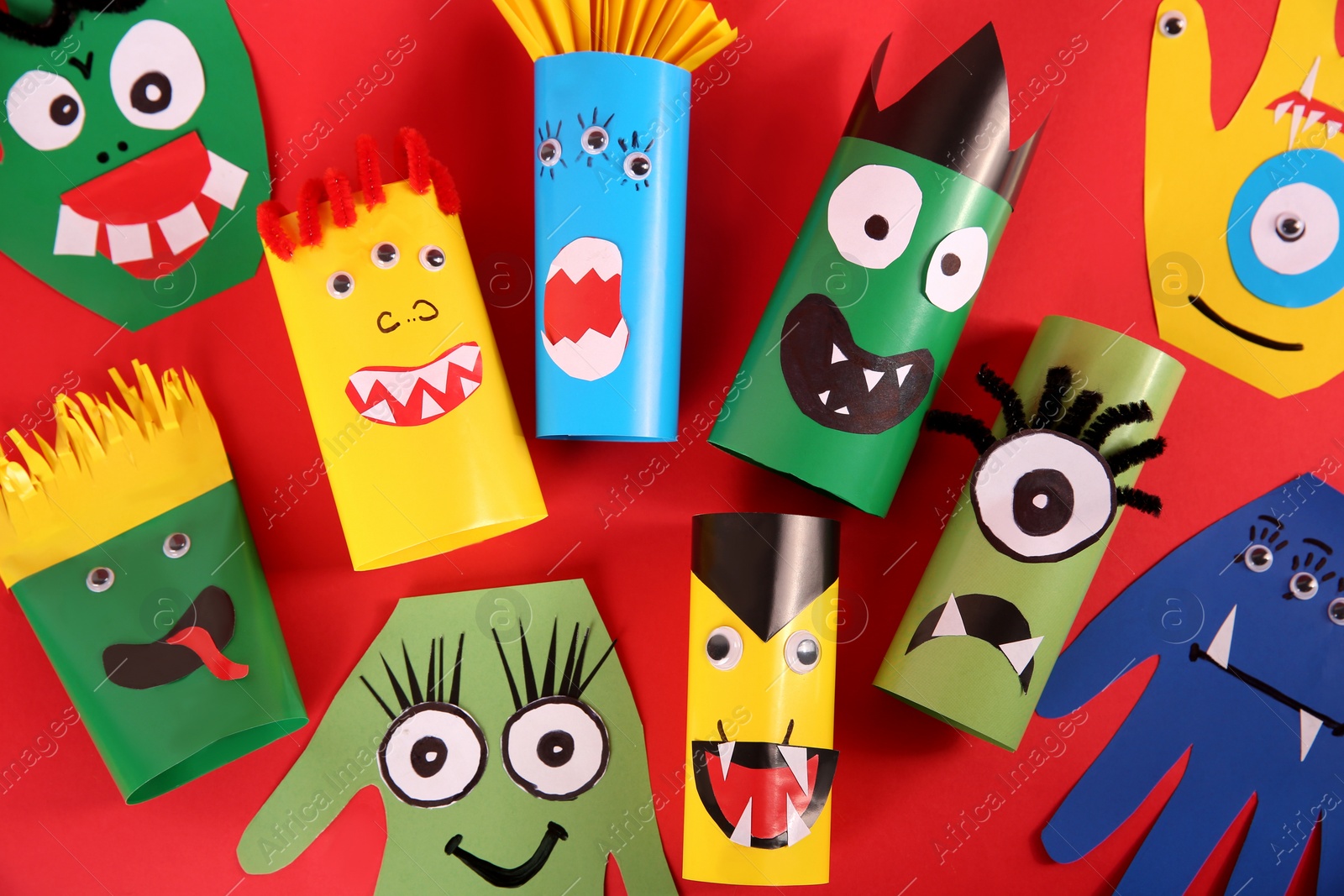 Photo of Funny monsters on red background, flat lay. Halloween decoration