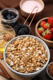 Tasty granola served with fresh berries and honey on table. Healthy breakfast