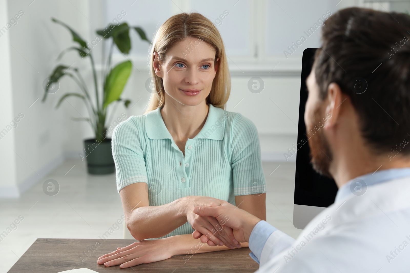 Photo of Doctor consulting patient at wooden table in clinic