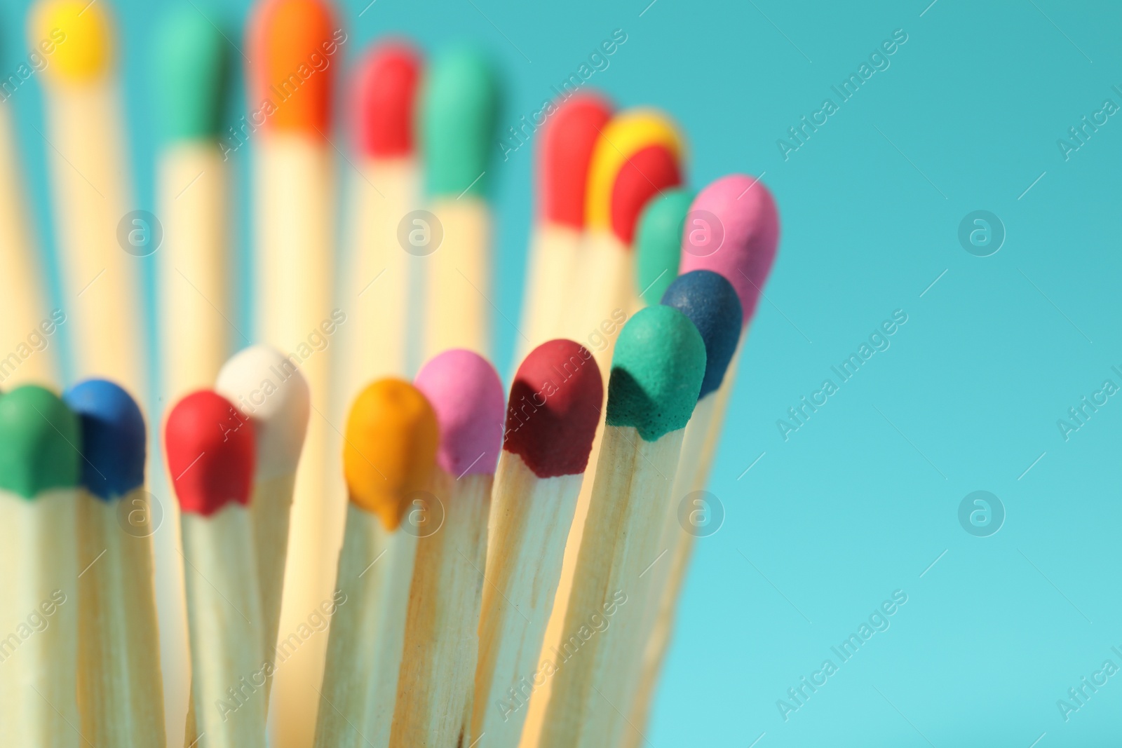 Photo of Matches with colorful heads on light blue background, closeup. Space for text