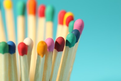Photo of Matches with colorful heads on light blue background, closeup. Space for text