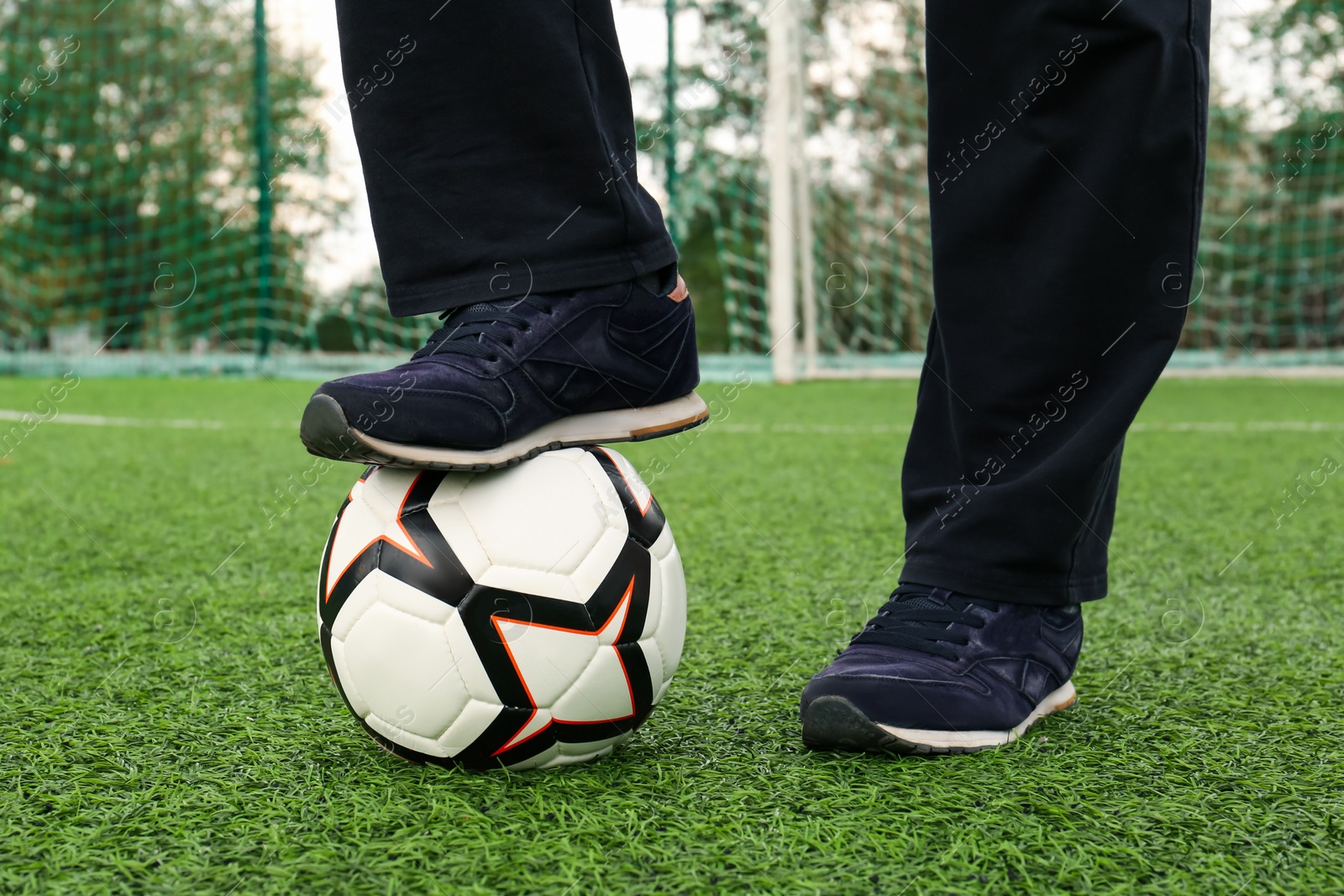 Photo of Man with soccer ball on green grass at stadium, closeup