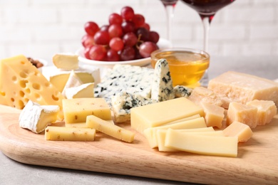 Photo of Plate with different sorts of cheese on grey table, closeup