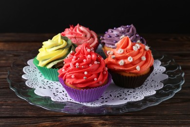 Photo of Delicious cupcake with bright cream on wooden table against black background