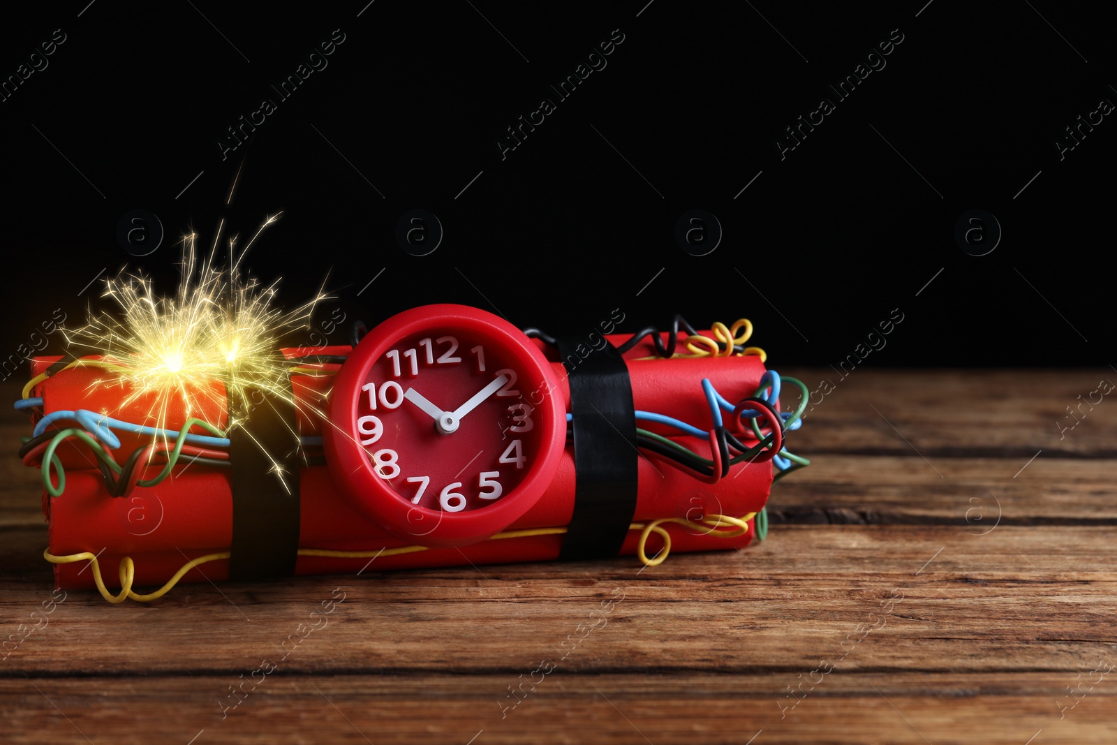 Image of Dynamite time bomb with burning wires on wooden table