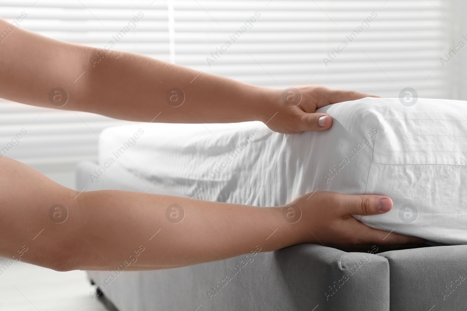 Photo of Woman covering mattress with protector indoors, closeup