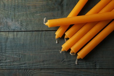 Many church wax candles on old wooden table, top view. Space for text