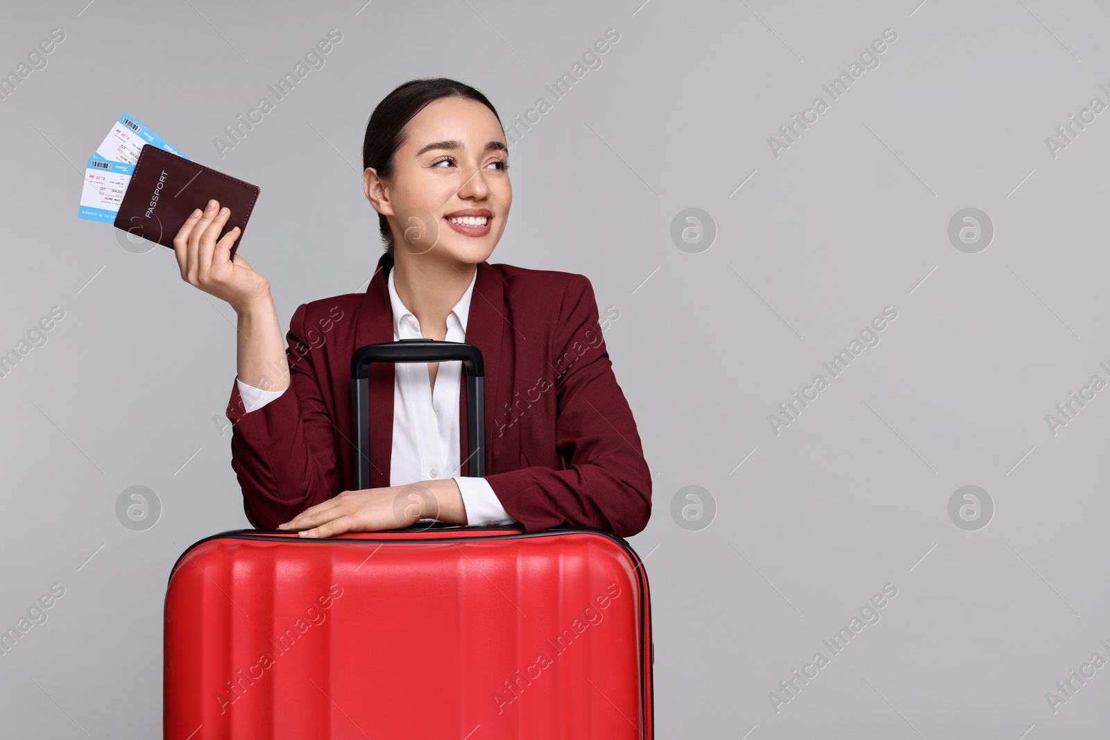 Photo of Happy businesswoman with passport, tickets and suitcase on grey background. Space for text