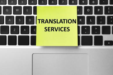 Image of Sticky note with phrase Translation Services on laptop, top view