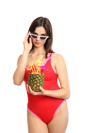 Beautiful young woman with exotic cocktail wearing swimsuit and sunglasses on white background