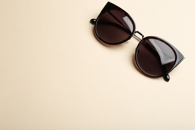 Stylish sunglasses on beige background, top view with space for text. Fashionable accessory