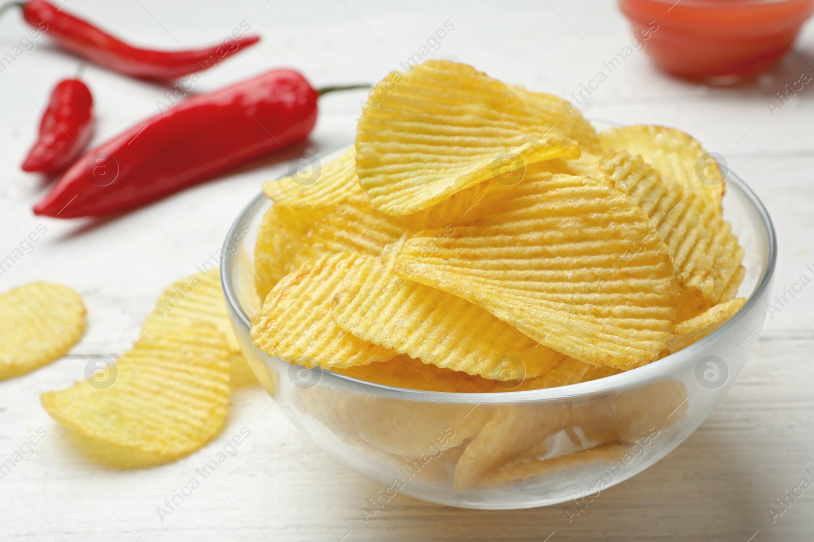 Photo of Delicious crispy potato chips in bowl on table, closeup