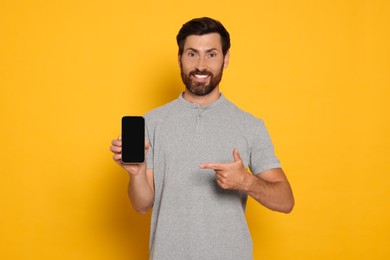 Photo of Happy man with smartphone on yellow background