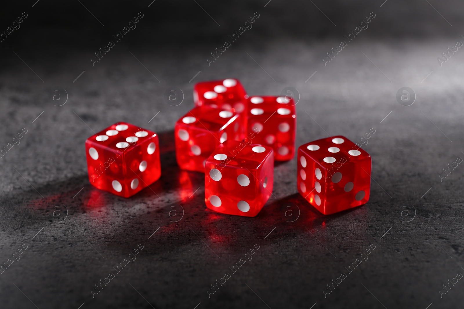 Photo of Many red game dices on grey textured table, closeup