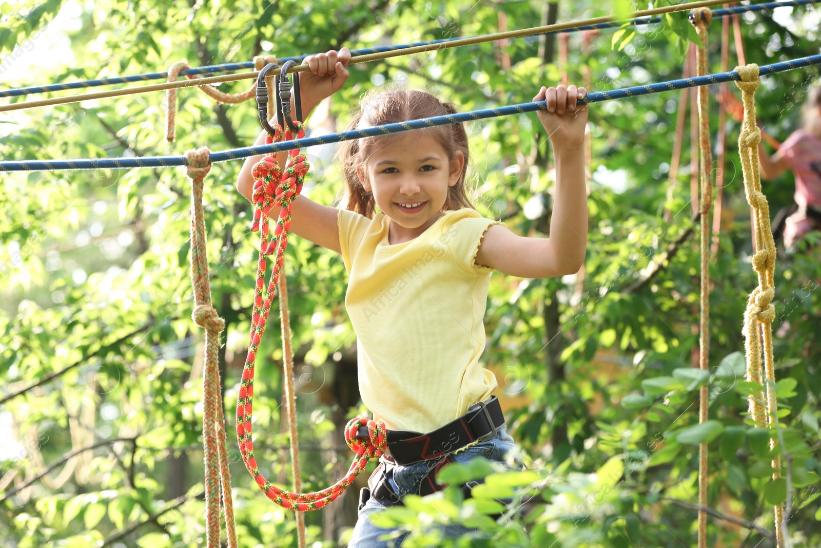 Photo of Little girl climbing in adventure park. Summer camp