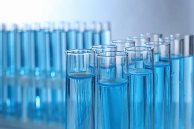 Photo of Test tubes with liquid against blurred background, closeup. Laboratory analysis
