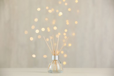 Aromatic reed air freshener on light table against blurred lights